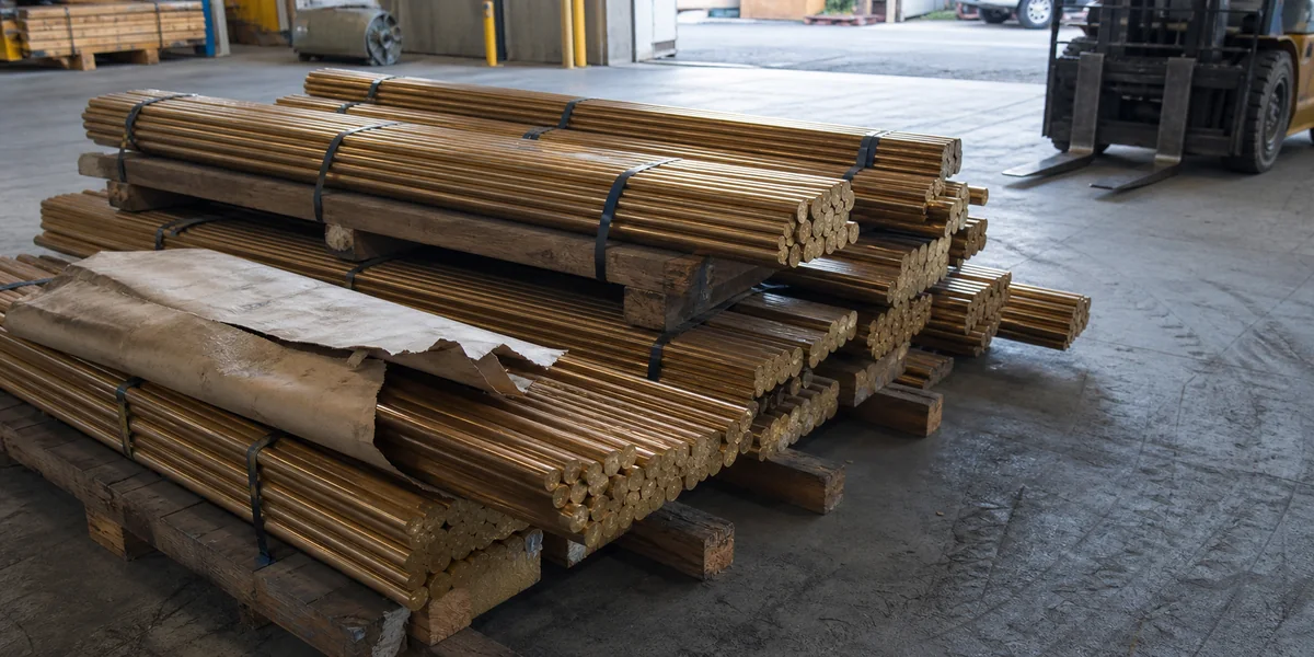 Bronze rod bundles on timber supports in a warehouse loading area